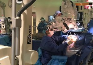 Skull-based surgery team at UConn Health is the first in the country to utilize novel ARveo microscope. with augmented reality capabilities. Dr. Dan Roberts (seated) doing his part of the complex skull-based surgery with Dr. Ketan Bulsara this July.