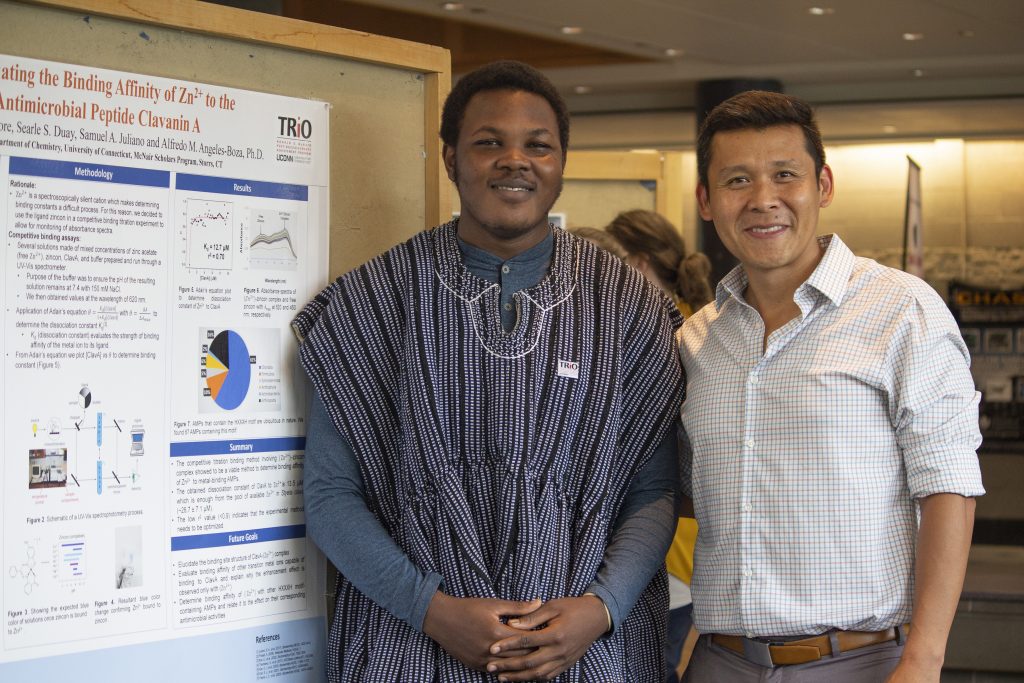Richmond Apore '19 (CLAS), a biological sciences major, with research mentor Alfredo Angeles-Boza, an assistant professor of chemistry, at the McNair Scholars Poster Session on July 25. The McNair program at UConn seeks to help low-income and first-generation students and those from underrepresented backgrounds prepare for graduate school and academic careers in STEM fields. (Christine Buckley/UConn Photo)