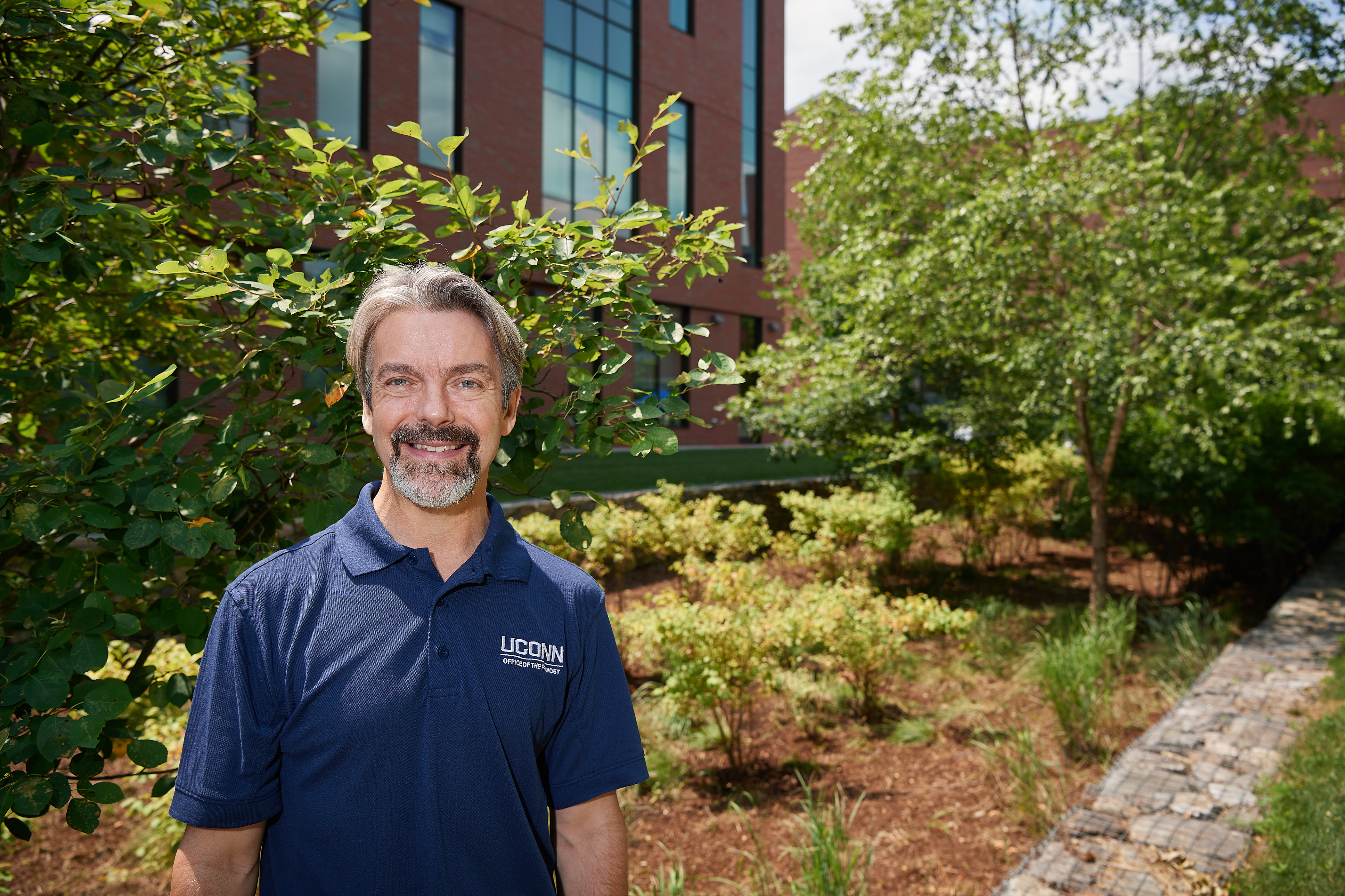 John Volin, vice provost for academic affairs and professor of natural resources and the environment, stands near a bioretention swale outside behind McHugh Hall on July 11, 2018. (Peter Morenus/UConn Photo)