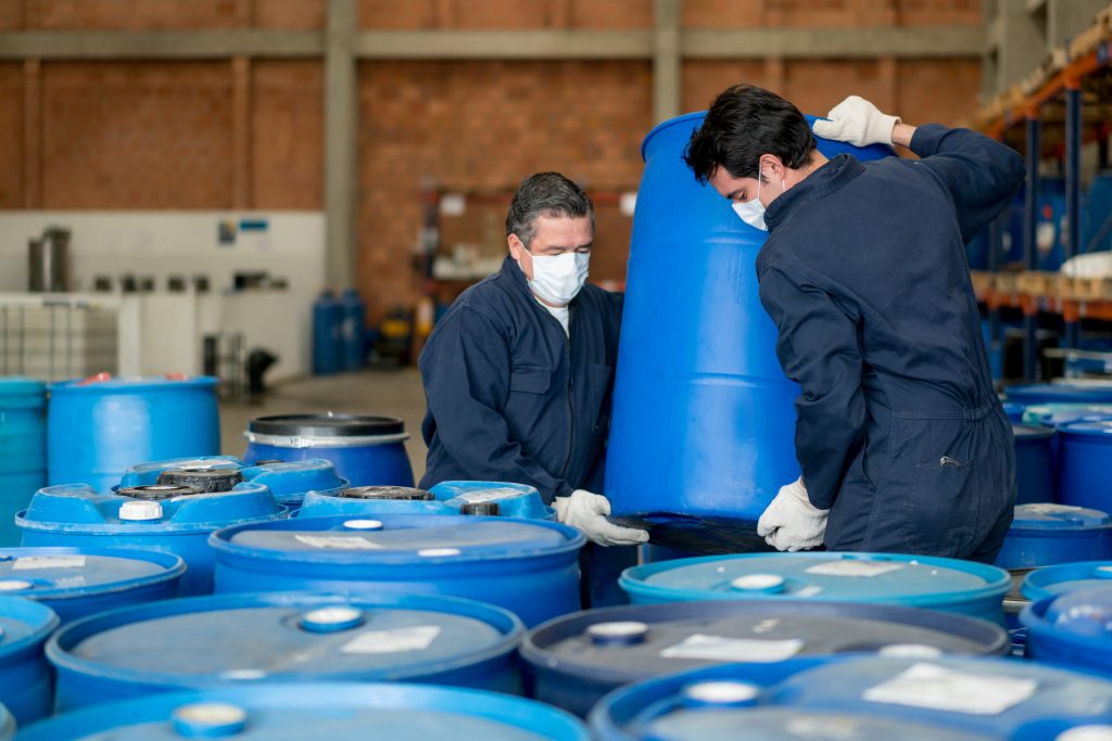Men working at a chemical plant carrying barrels with toxic products. (Getty Images)