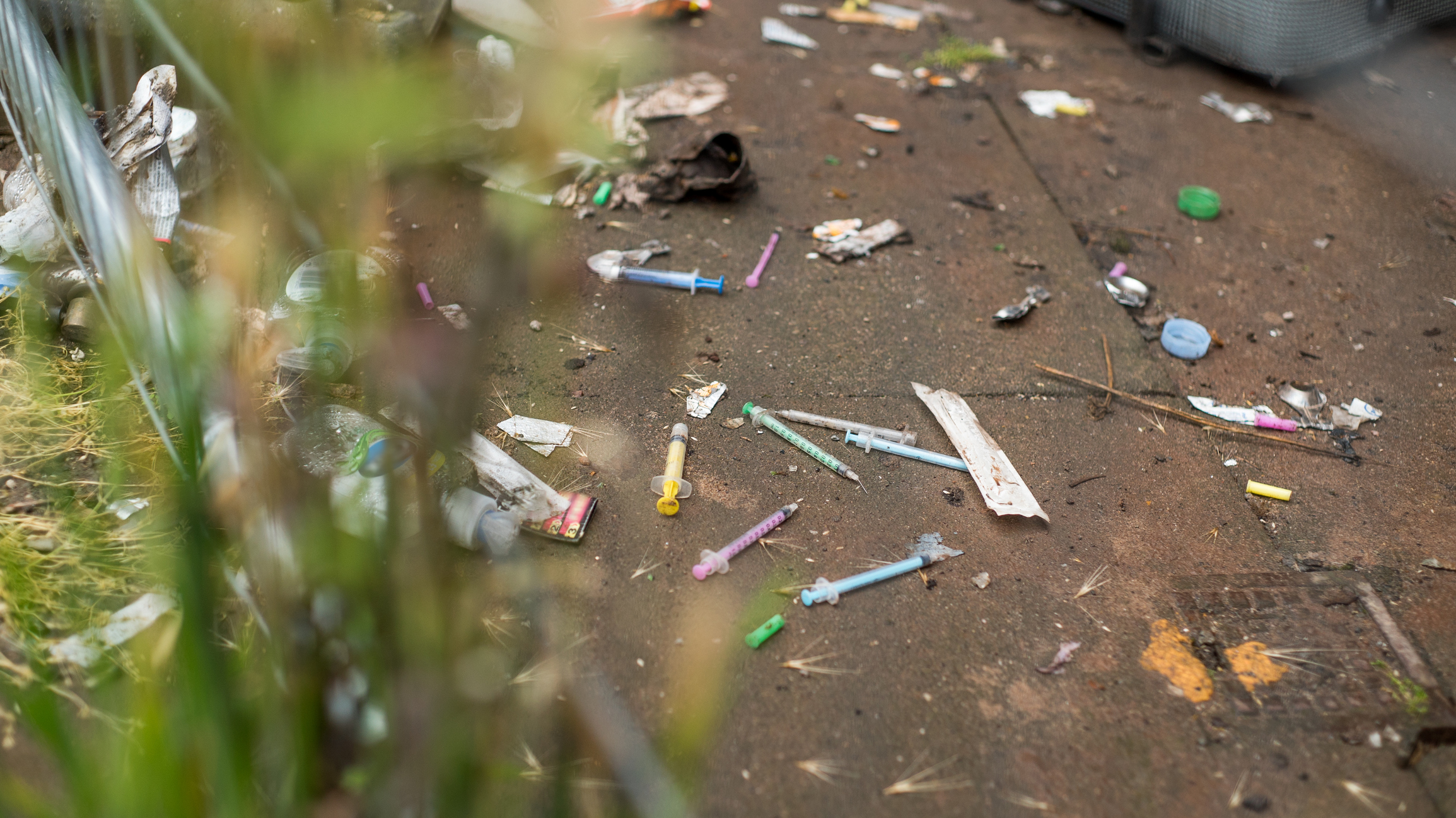 Syringes scattered on a litter strewn pavement. (Getty Images)