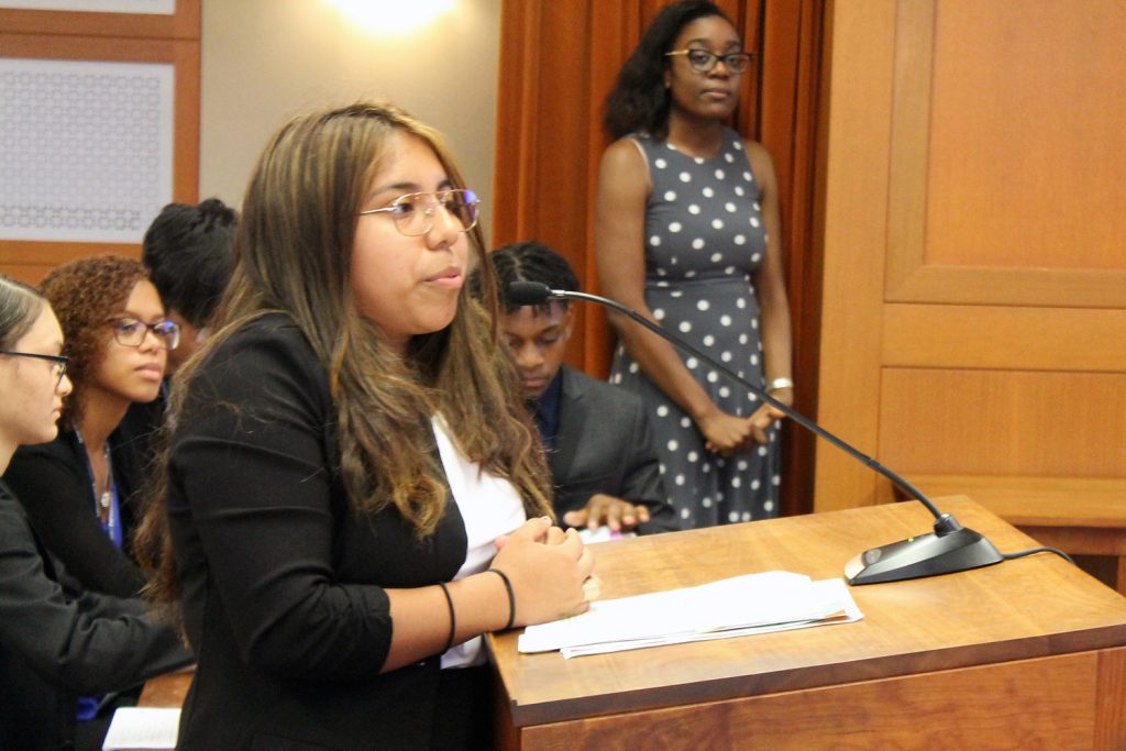 Hartford Public High School student Jasmine Jara presents the prosecution’s case in a mock trial at UConn School of Law. In the background, from left, are fellow students, all members of the defense team, Frances Reyes, Dalice Gonzalez, Zam Khai, and Nick Simmonds, and a member of the teaching team, Alexandria McFarlane’18 JD.