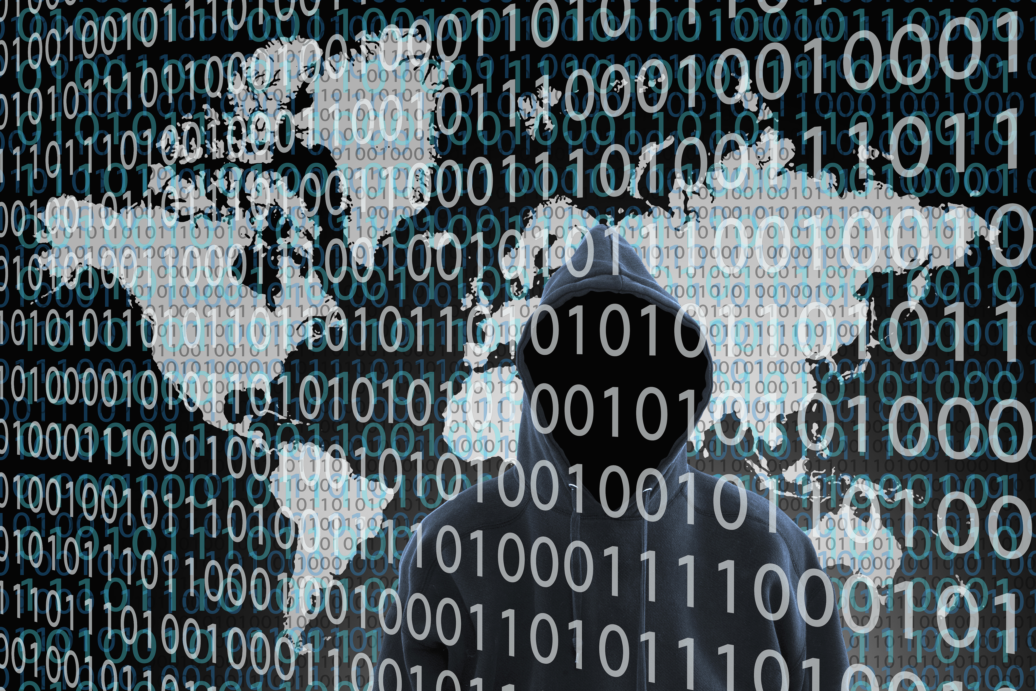 Hacker wearing hoody standing behind binary code. (Getty Images)