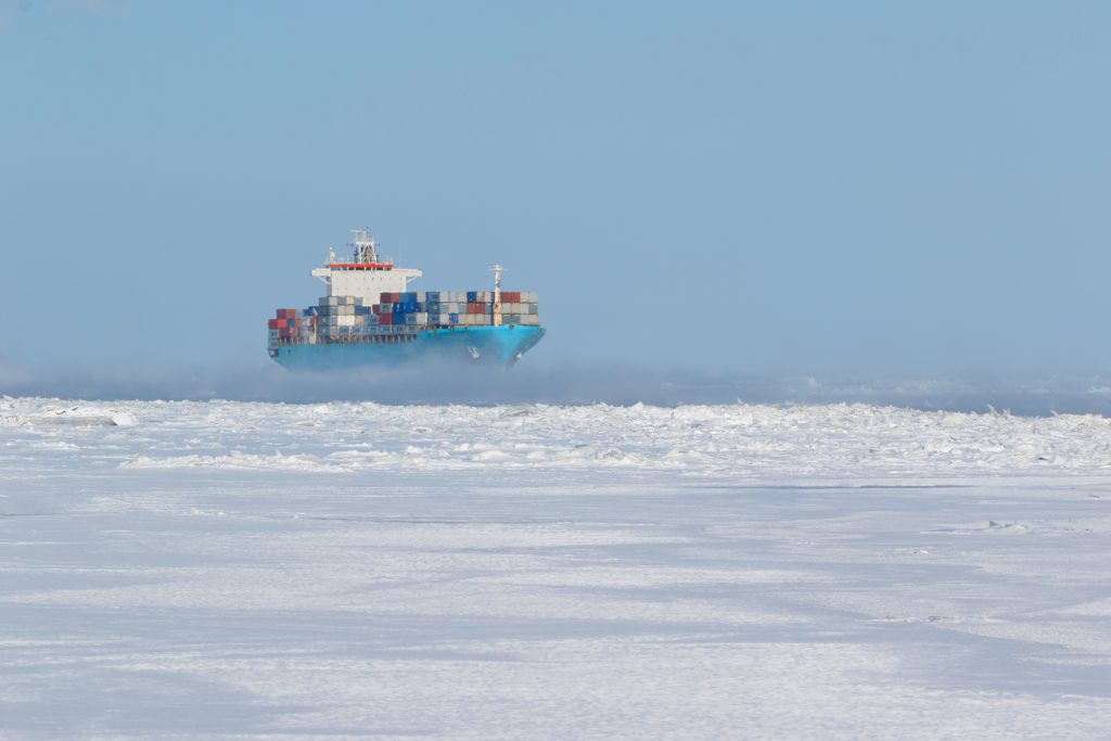 Large cargo filled with containers navigating through ice-surrounded passage. (Getty Images)