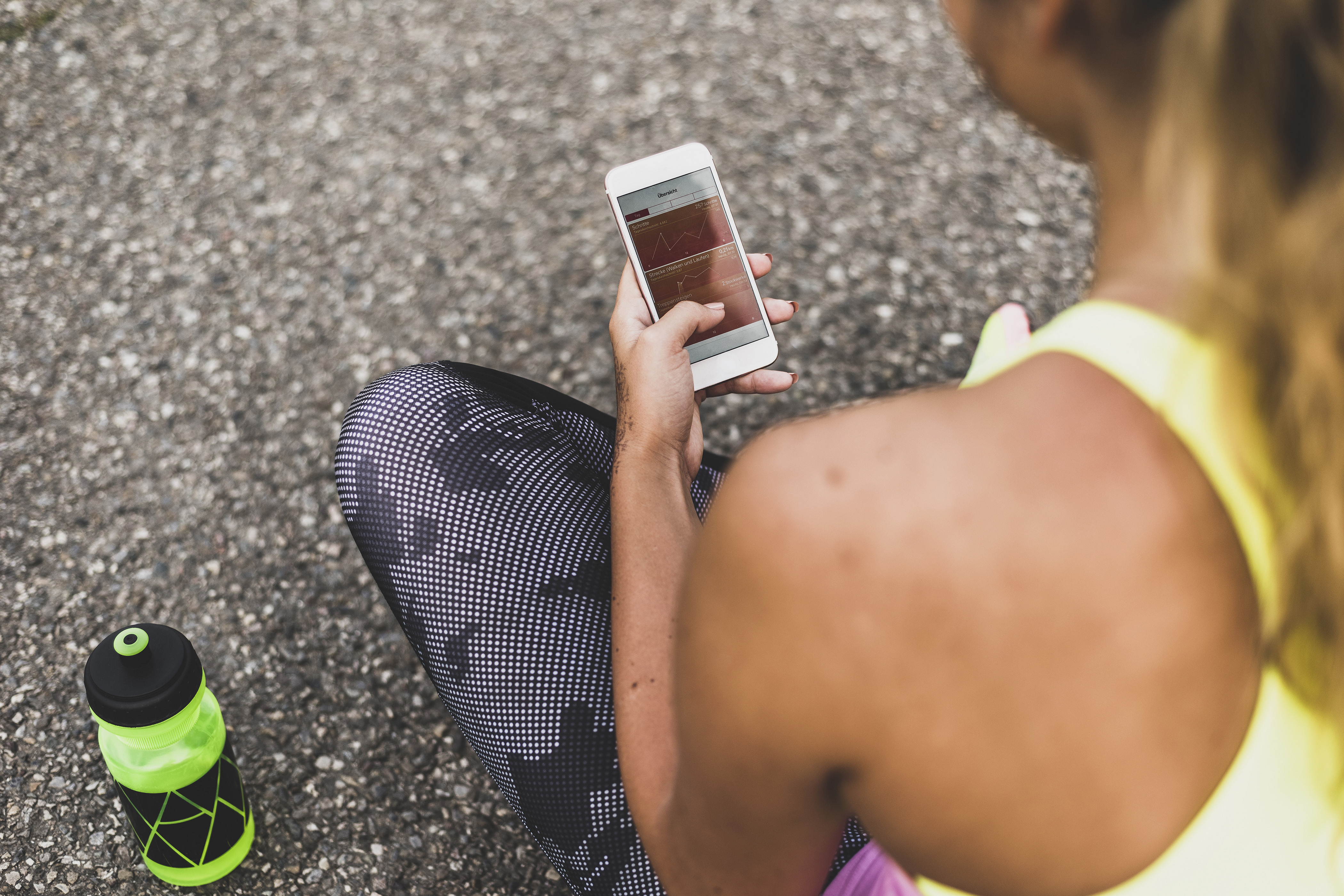 A young woman in exercise attire looks at health information on her cell phone. (Getty Images)