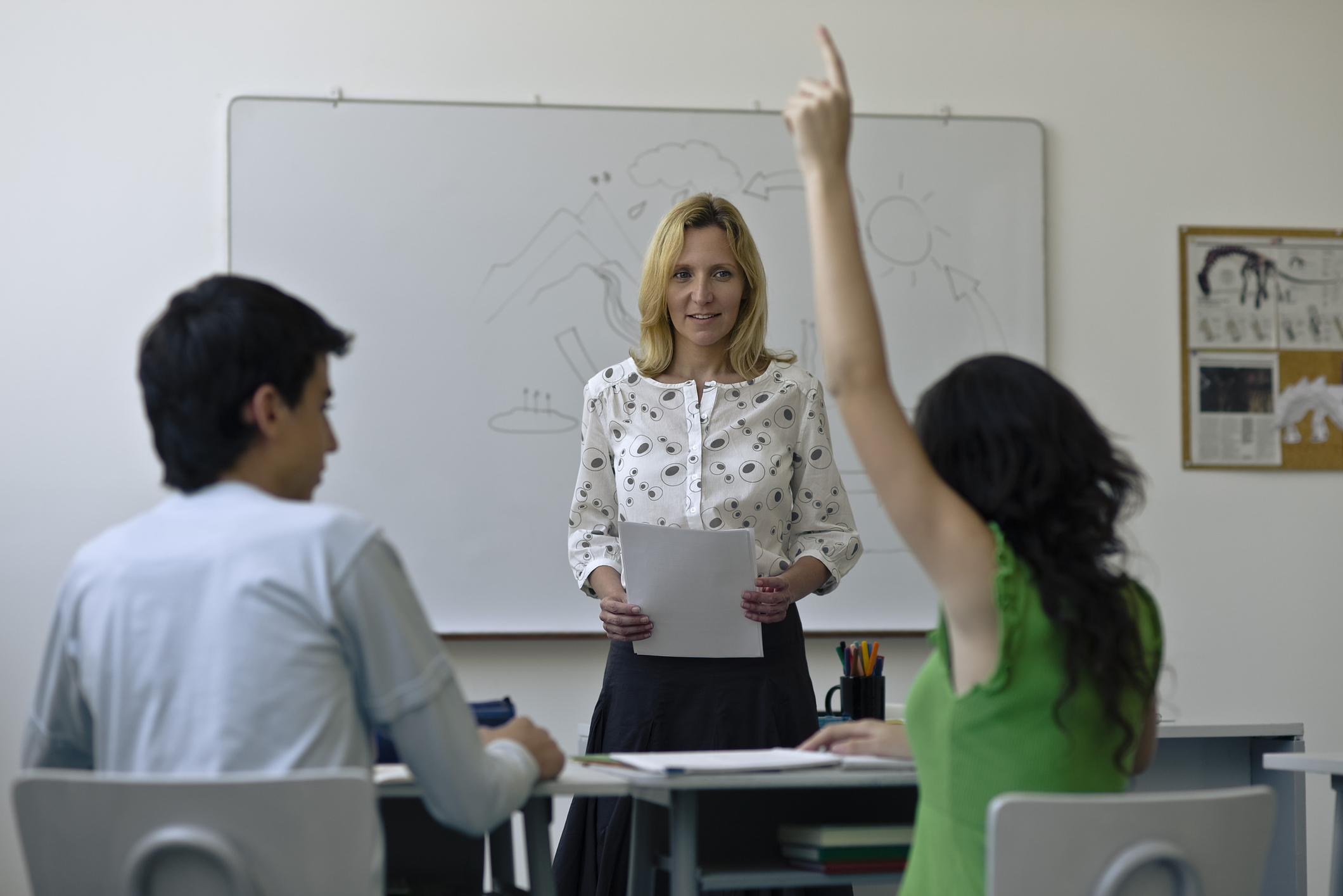 High school teacher in classroom, one student raising hand. (Getty Images)