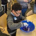 Jayson Wilson mixes together a solution that will become slime that the kids will take home in bags to play with. (Lucas Voghell '20 (CLAS)/ UConn Photo)