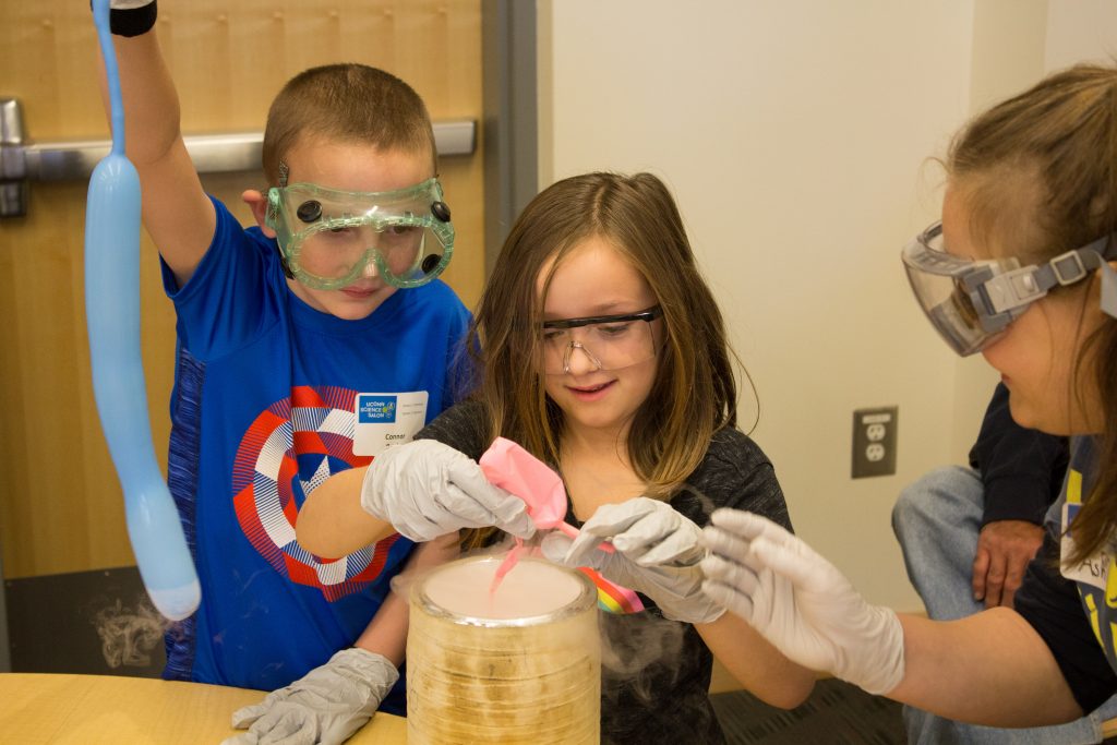Connor Beebe and Addison Esposito dip balloons in liquid nitrogen with the help of Ashley Orcutt, a program assistant for the Chemistry department.
