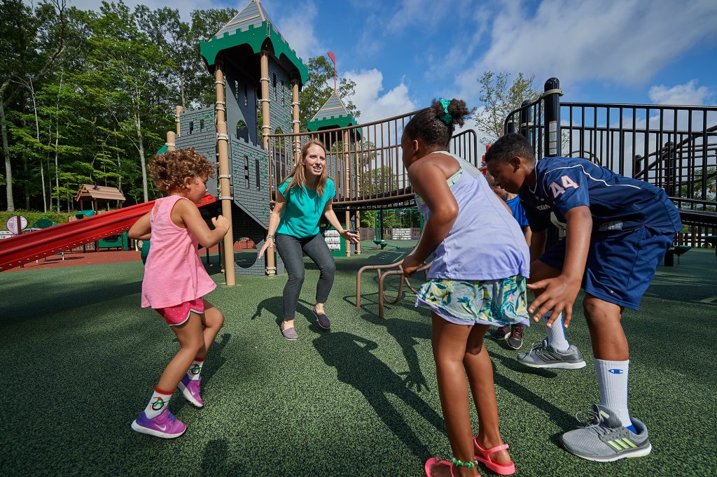 Lindsay Distefano, associate professor of kinesiology,shows children how to exercise on a playground at the Mansfield Community Center on Aug. 3, 2018. (Peter Morenus/UConn Photo)
