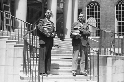President Albert Jorgensen, left, and university librarian Paul Alcorn provided hands-on help with moving books into the new library in 1940. The building was named for former Connecticut governor Wilbur Cross in 1942. (University Library Archives & Special Collections)