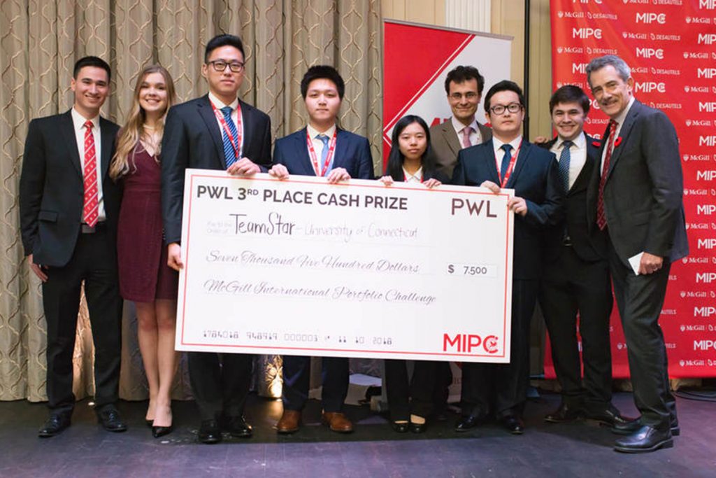 UConn students, from left, Junchao Liao, Xiofan Hou, Xiao Wang and Tuershunjiang Ahemaitijiang hold their check after being recognized as the top U.S. team at the McGill International Portfolio Challenge in Montreal earlier this month. They are surrounded by event organizers. (Photo Courtesy of Jose Aponte)
