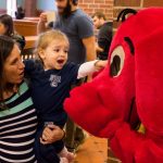 Allegra Martineau, 22 months, in the arms of her mother Maria, reaches out to touch Clifford the Big Red Dog’s nose. (Lucas Voghell '20 (CLAS)/UConn Photo)