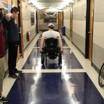Senior biomedical engineering majors Mitchell DuBuc, James Welch, and Alex Draper, under the advisement of Professor Krystyna Gielo-Perczak, are putting a new type of wheelchair wheel to the test for their Senior Design project. Here, Mitchell DuBuc, center, a wheelchair user, tests the new wheels in the Arthur B. Bronwell Building. (Eli Freund/UConn Photo)