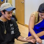 Conor Merchant receives a temporary tattoo from Keshini Hiniduma of the ISA, the Indian Student Society. (Lucas Voghell '20 (CLAS)/UConn Photo)