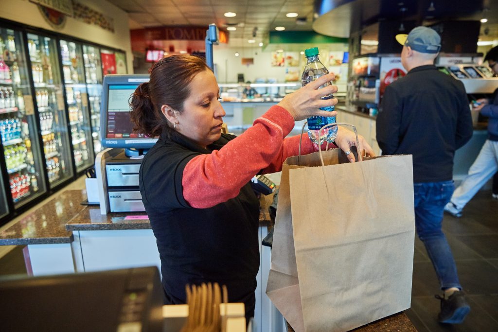 Patricia Ruffino, a cashier at the Union Street Market, fills a paper bag with a purchase. (Peter Morenus/UConn Photo)
