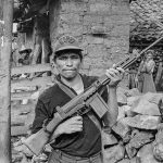 A rebel militiaman hoists his rifle in a gesture of defiance in front of his home in rebel-occupied Chalatenango Department, El Salvador, 1984. (Scott Wallace)