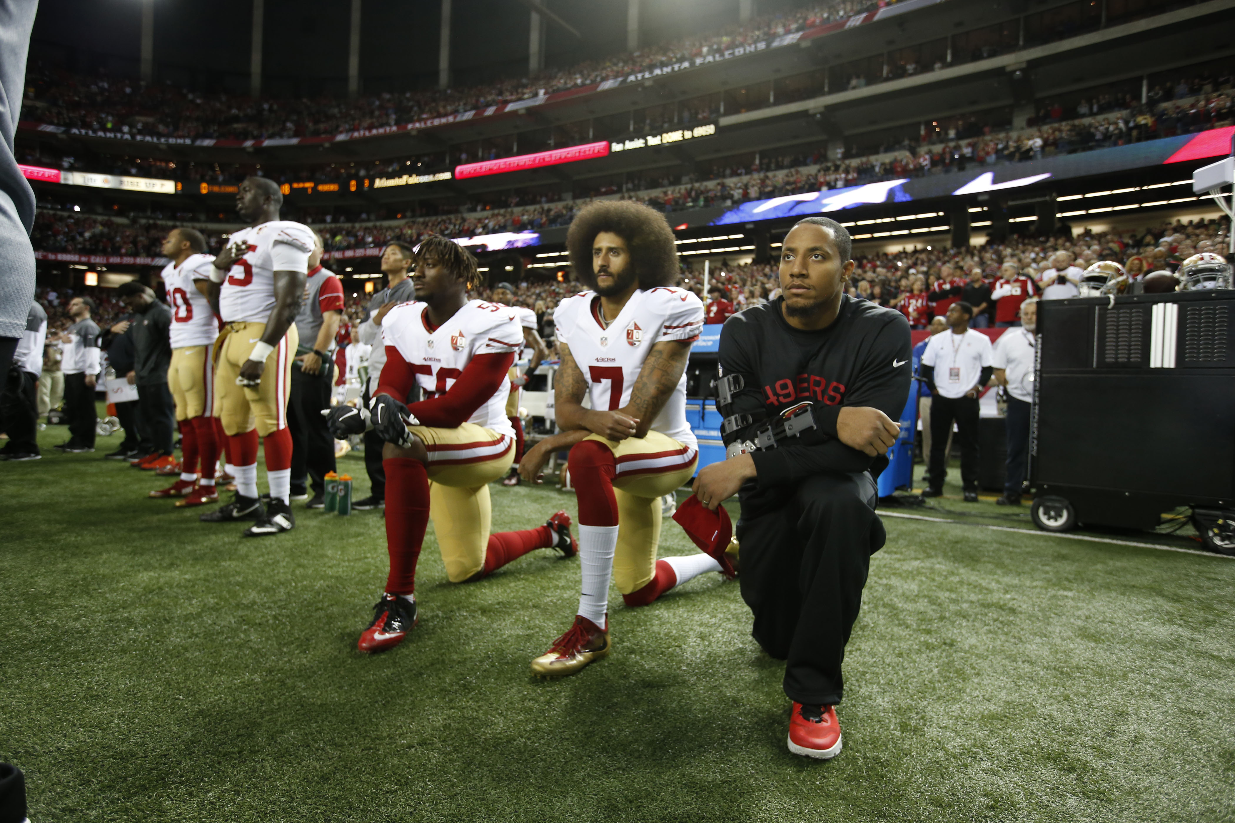 NFL player Colin Kaepernick, foreground center, kneels during the playing of the National Anthem to rally support for social justice. When the response to a protest is not to engage on the actual issue but to instead talk about whether the protesters protested appropriately, it’s a way of changing the subject, says sociologist Ruth Braunstein. (Getty Images)