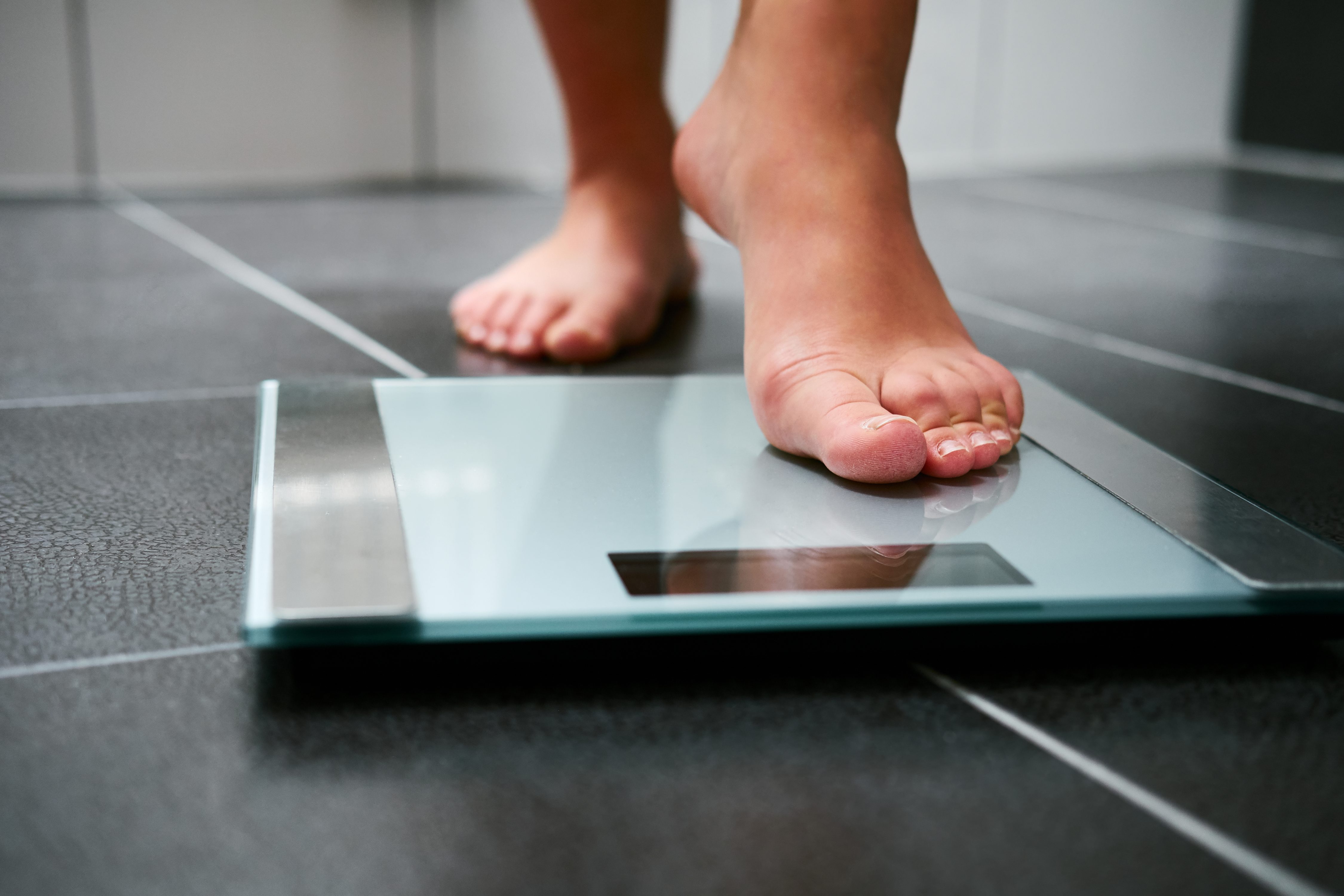 Female bare feet with weight scale in the bathroom. (Getty Images)