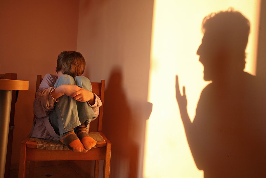 Young boy cowering from shadow of yelling parent