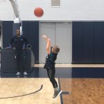 Rylan takes a shot on the practice court at the Werth Family Basketball Champions Center, as Taliek Brown, director of student-athlete development, looks on. (UConn Men's Basketball Photo)