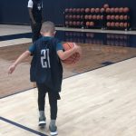 Alterique Gilbert encourages Rylan as he warms up on the practice court at the Werth Family Basketball Champions Center. Rylan is wearing a jersey with Mamadou Diarra's number, 21. (UConn Men's Basketball Photo)