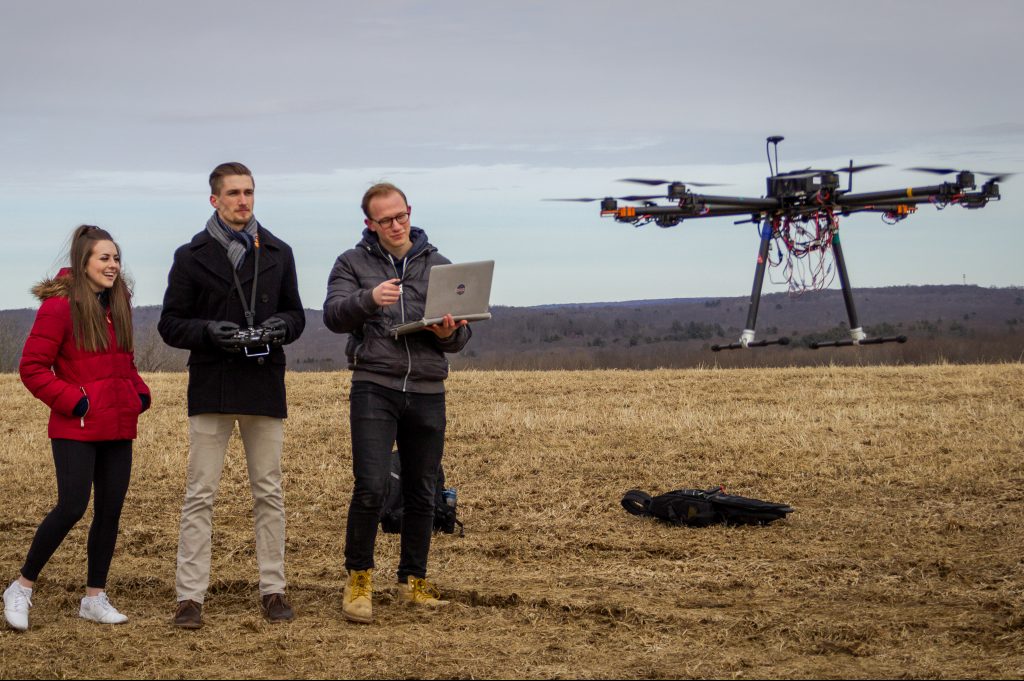 From left, Kerry Jones '19 (ENG), Ryan Heilemann '19 (ENG), and Josh Steil '19 (ENG) look on as their drone takes off for a test flight on Horsebarn Hill in Storrs. (Christopher Larosa/UConn Photo)
