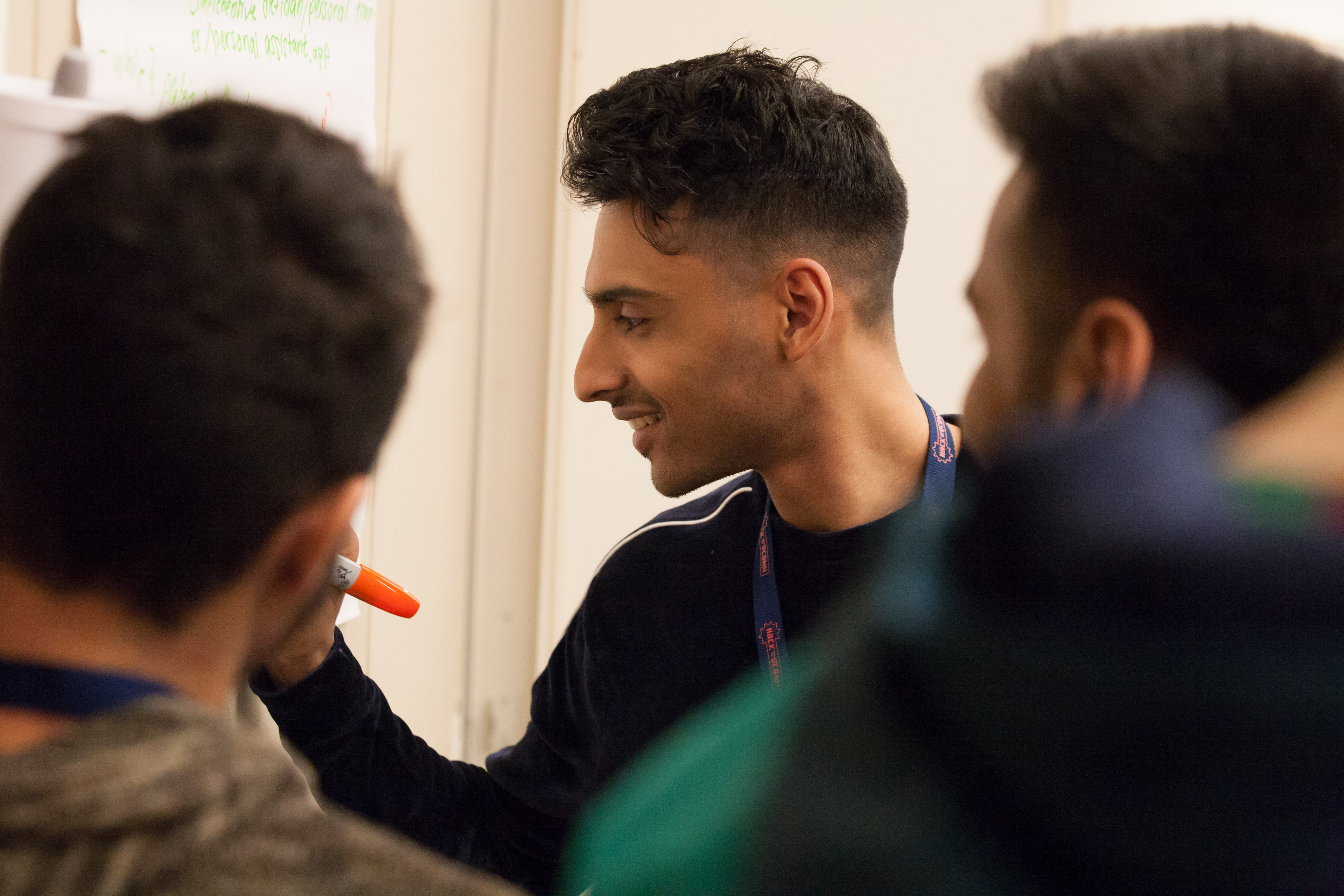 Vishal Cherian ’19 (ENG) writes some of his ideas on the pieces of paper posted along the wall. (Lucas Voghell ’20 (CLAS)/UConn Photo)