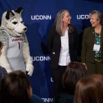 Jonathan the Husky, left, Ellyssa Eror of Student Health Services, and Mary Ann Phaneuf of the School of Pharmacy wait as President Herbst announces the winner of the unsung hero award during the Spirit Awards ceremony. (Peter Morenus/UConn Photo)