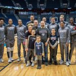 Daniela with the Women's Basketball team and family members on Junior Husky Club day at Gampel Pavilion on Jan. 27, 2019: her mom, Nicole, and dad, Daniel, sister Angelina (10), brother Dominic (12), and, in the arms of Batouly Camara, brother Matteo (2). (Jason Reider/Athletic Marketing Photo)