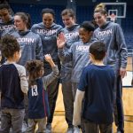 Daniela gives a high five, as members of the Women's Basketball team and Daniela's family look on, on Junior Husky Club day at Gampel Pavilion on Jan. 27, 2019. From left, her mom, Nicole, sister Angelina (10), and brother Dominic (12). (Jason Reider/Athletic Marketing Photo)