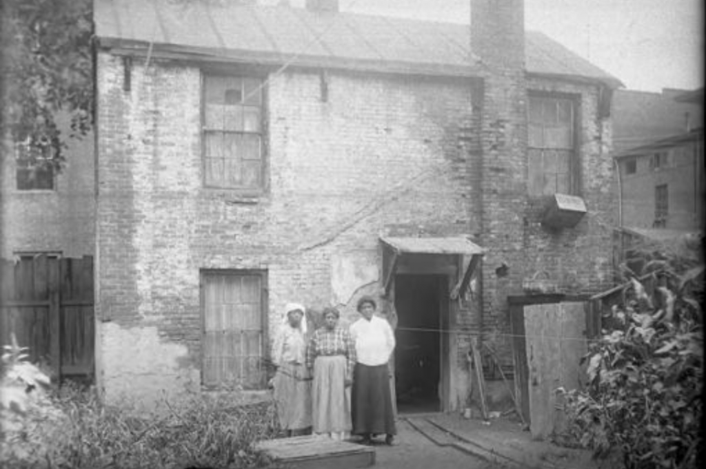 Three African-American women stand in front of east side tenements on Pearl Street in Hartford, circa 1900-1920. (Courtesy of the Hartford History Center, Hartford Public Library)
