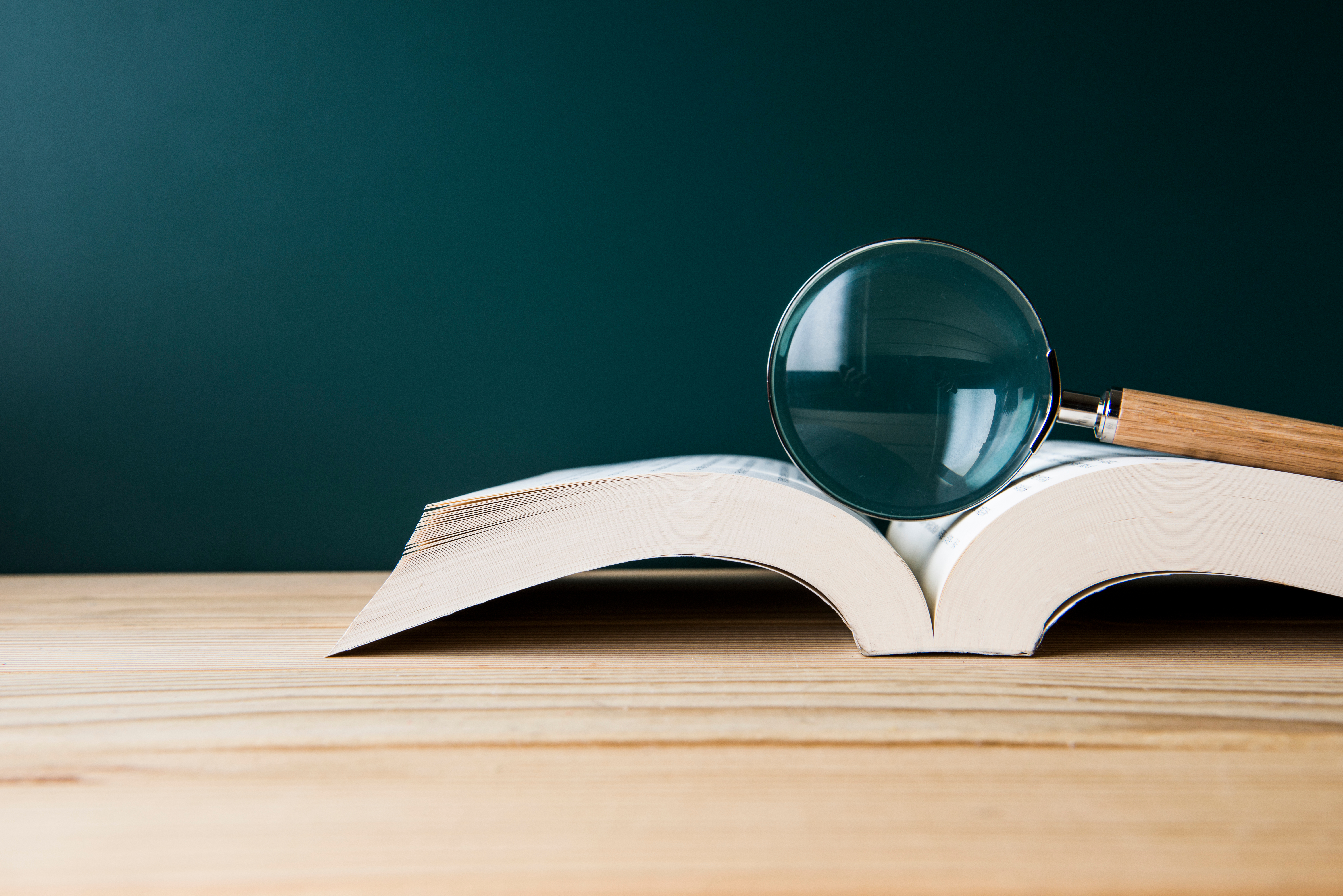 Magnifying glass resting on a book. (Getty Images)