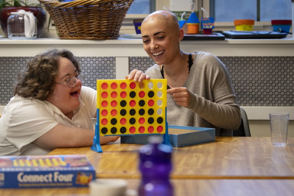 At right, Vanessa Rosa ’19 (CLAS) and April play Connect Four in Sprague Residence Hall. Vanessa and April are part of the Best Buddies/STAAR program where undergraduate students are mentors to young adults with developmental disabilities. April 26, 2019. (Sean Flynn/UConn Photo)