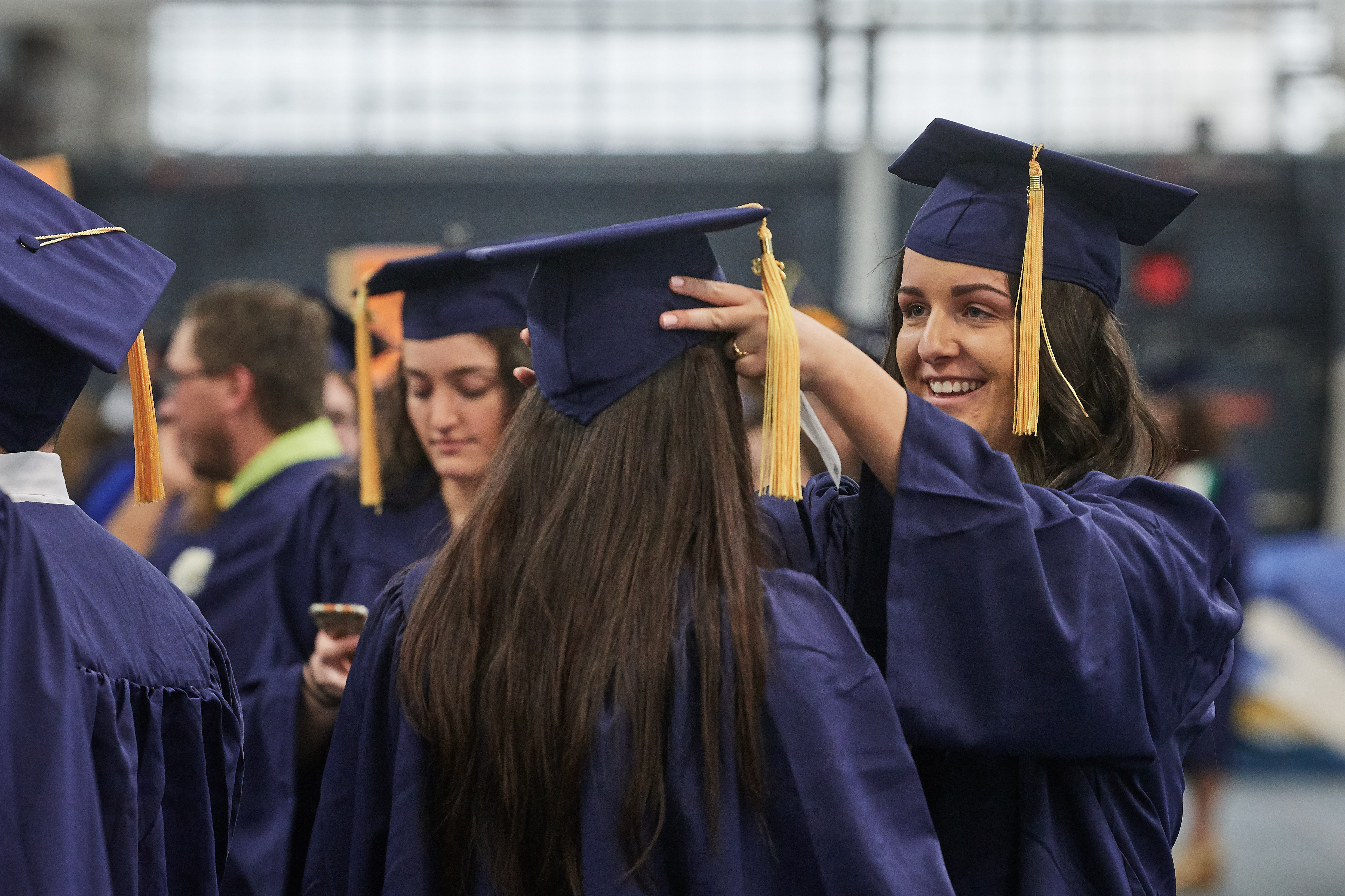 Bridgette Collier '18 (CAHNR), right, helps Mariah Lombard '18 (CAHNR) with her cap at Greer Field House before the College of Agriculture, Health, and Natural Resources Commencement procession on May 5, 2018. (Peter Morenus/UConn Photo)