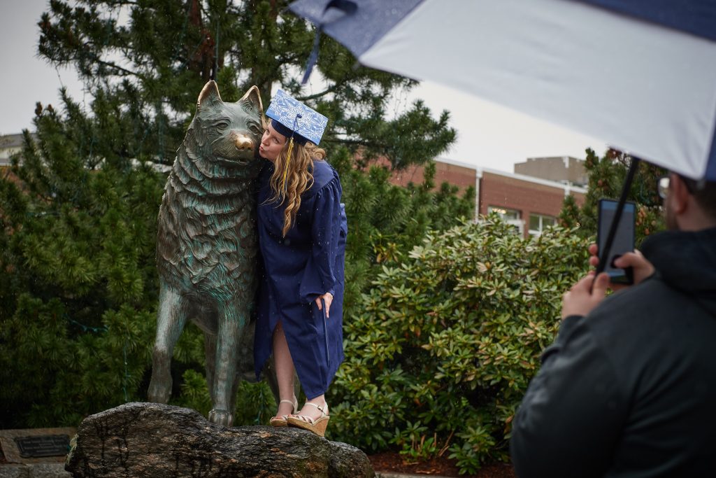 Hannah Steinke gives the husky statue a kiss on the nose following College of Liberal Arts & Sciences commencement ceremony on May 12. (Peter Morenus/UConn Photo)