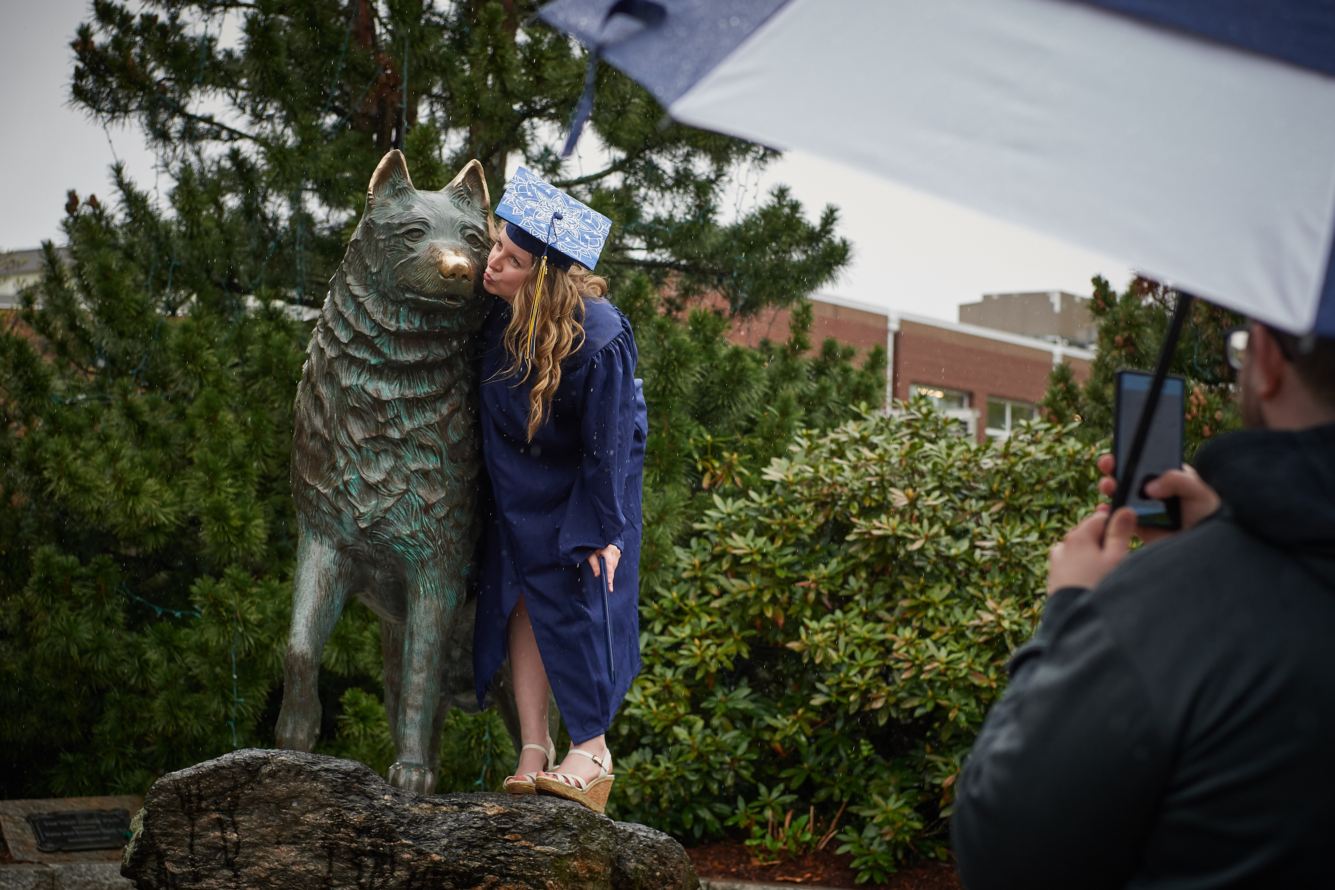 Hannah Steinke gives the husky statue a kiss on the nose following College of Liberal Arts & Sciences commencement ceremony on May 12. (Peter Morenus/UConn Photo)