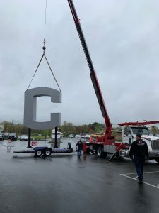 Workers hoist the letter C into place as part of the new UCONN sign on Route 195, at the north entrance to the Storrs campus.