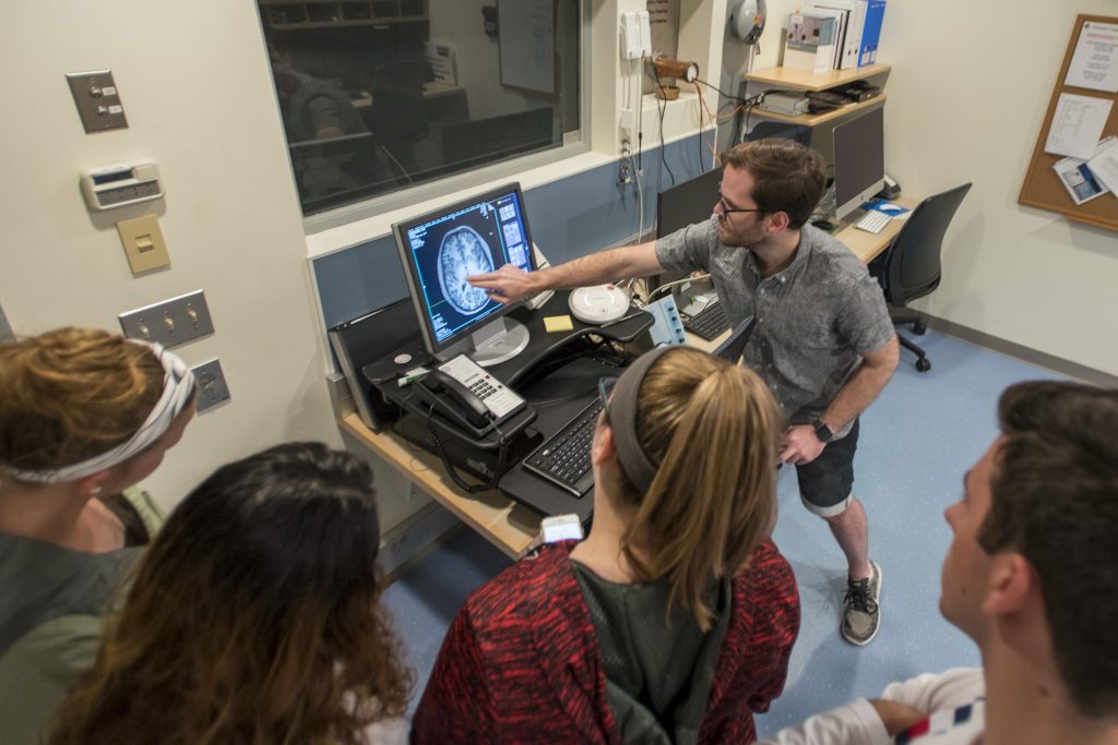 Charles Davis, a graduate student in psychology, shows an axial image of the brain to the group of local high school students. (Sean Flynn/UConn Photo)