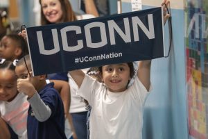 First-grader Emily Garcia holds up a UConn Nation banner during UConn Day at Kennelly School in Hartford on May 2, 2019. (Sean Flynn/UConn Photo)
