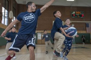 Third-grader Jonathan Rios charges the basket, as school social worker Nelson Veras '14 (CLAS), '18 MSW, attempts a block, during a basketball game of kids vs teachers at Kennelly School on May 2, 2019. (Sean Flynn/UConn Photo)