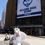 Jonathan the Husky and Jonathan XIV pose for a photo near a marquee welcoming UConn back to the Big East athletic conference outside Madison Square Garden on June 27, 2019. (Peter Morenus/UConn Photo)