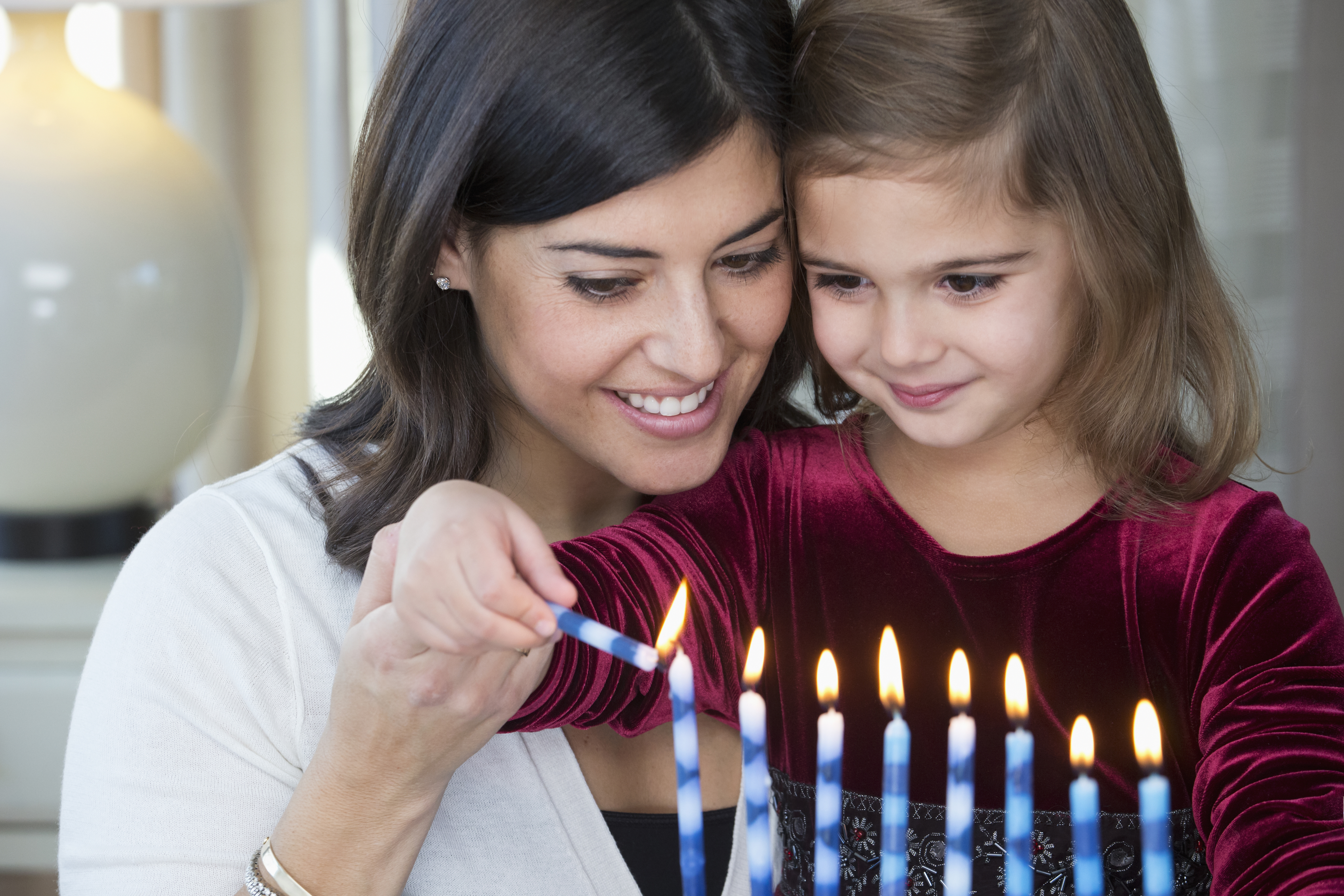 A mother and daughter lighting candles on a Hanukkah menorah. (Getty Images)