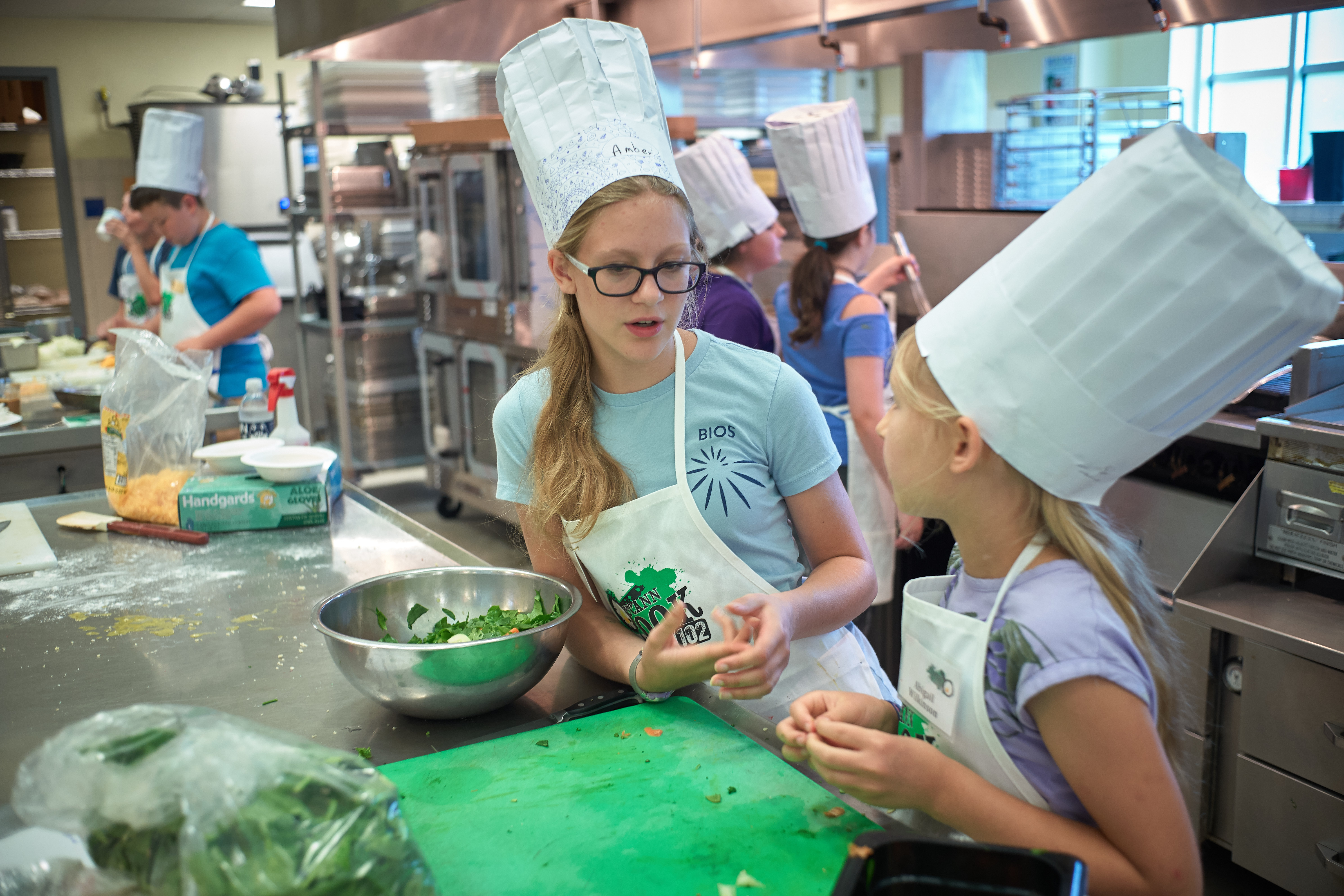 Amber Recchia, 13, of Ashford, center, and Abigail Wilkinson, 9, of Norwich, discuss ingredients to use for a salad dressing during a cooking competition held at the UCann Cook Camp at Gelfenbien Commons on July 18, 2019. (Peter Morenus/UConn Photo)