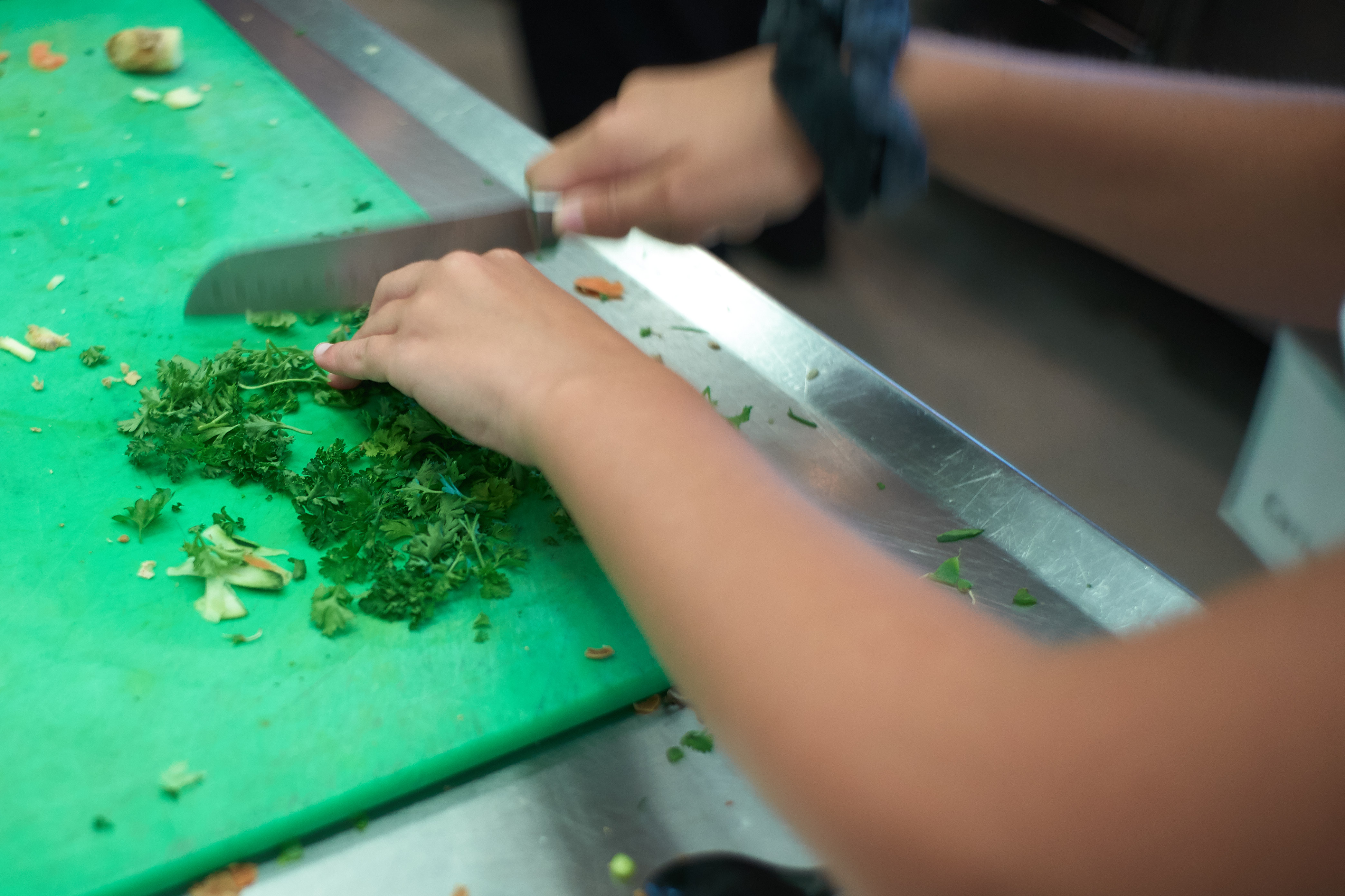 Chopping herbs to be included in a salad dressing during a competition held at the UCann Cook Camp at Gelfenbien Commons on July 18, 2019. (Peter Morenus/UConn Photo)