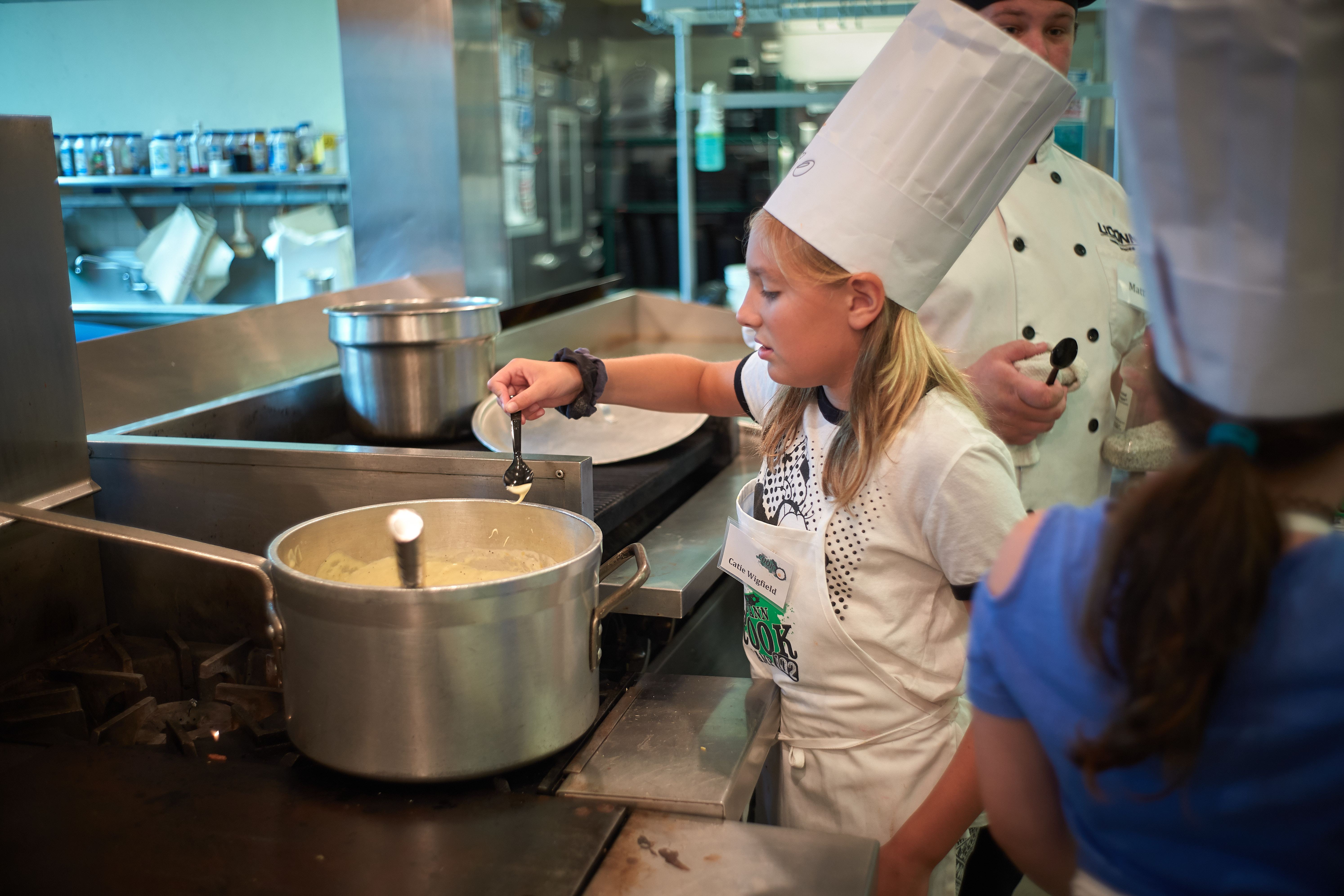 Catie Wigfield, 10, of Baltic, takes a taste of cheese sauce during a competition held at the UCann Cook Camp at Gelfenbien Commons on July 18, 2019. (Peter Morenus/UConn Photo)