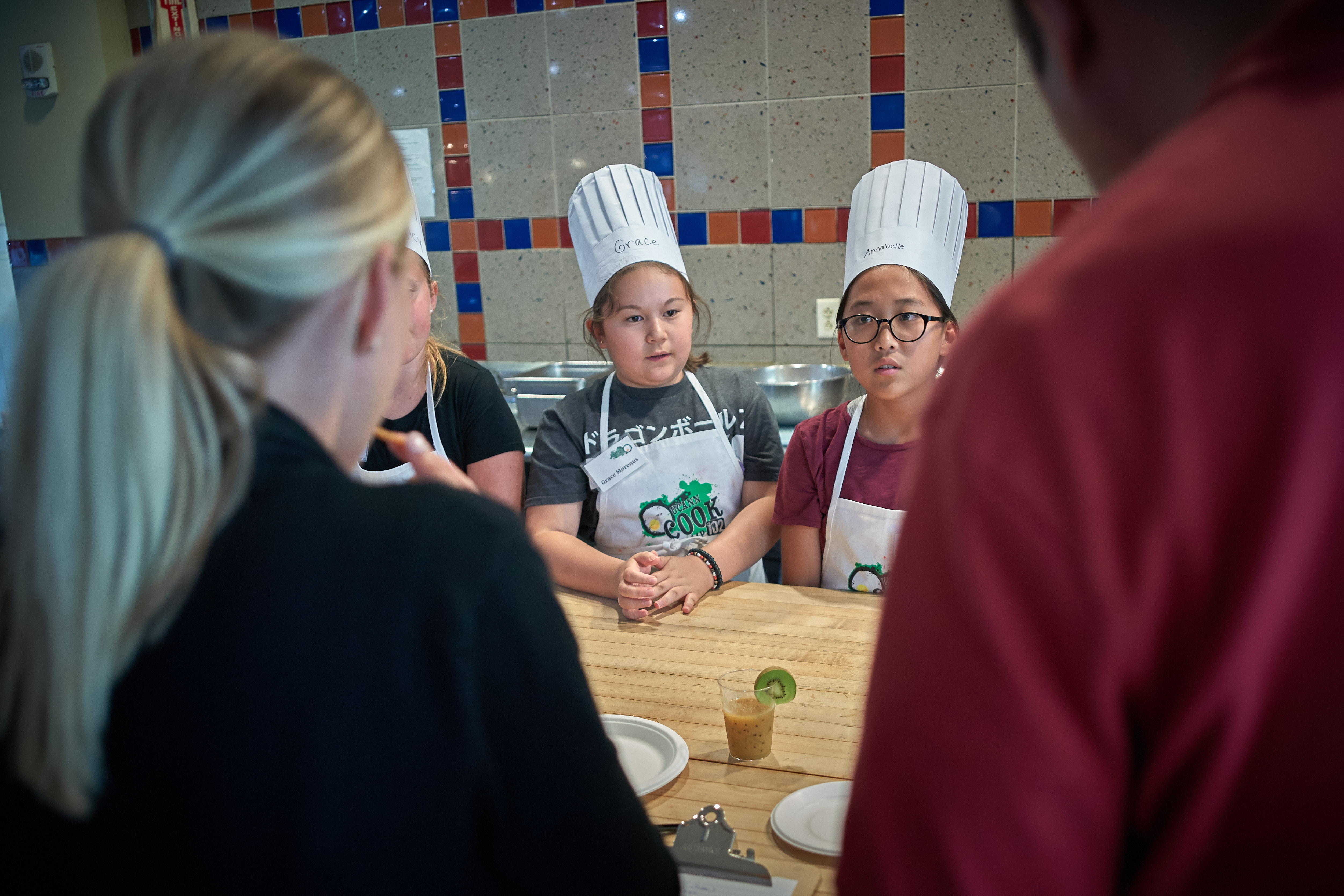 Grace Morenus, 10, of Willimantic, second from left, and Annabelle Kim 11, of South Windsor, answer questions about their team entry during a competition at the UCann Cook Camp at Gelfenbien Commons on July 18, 2019. (Peter Morenus/UConn Photo)