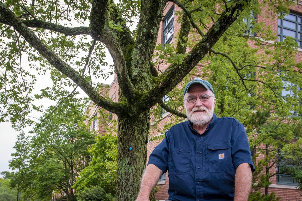 Associate extension professor Tom Worthley sitting next to an established hackberry tree, a native species, outside the Young Building . (Sean Flynn/UConn Photo)