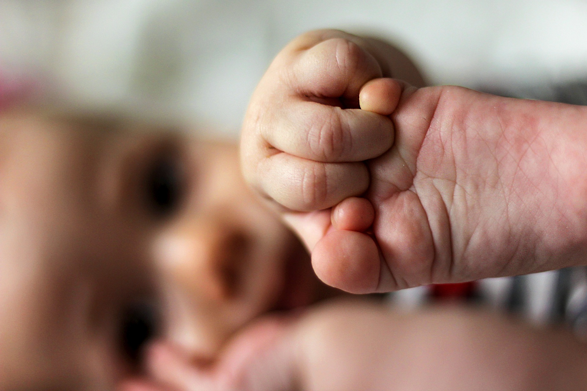 Close up of infant holding its foot.