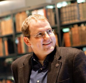 Headshot of Jeffrey McCutcheon, caucasian male, smiling in a library