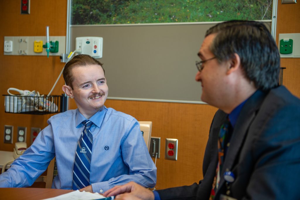 Jerrod Watts, a patient enrolled in the first clinical trial for Glycogen Storage Disease, chats with lead investigator Dr. David Weinsten. Photos taken in the dedicated Glycogen Storage Disease Unit at UConn Health on July 16, 2019. (Tina Encarnacion/UConn Health photo)